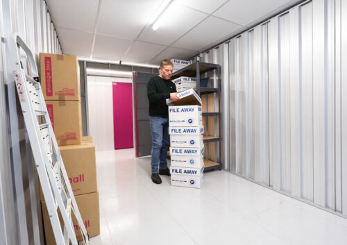 Man moving boxes inside a self storage unit at The Store Room